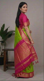 Load image into Gallery viewer, Woman wearing a green and pink saree with a plant in the background
