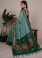 Load image into Gallery viewer, Woman wearing a green saree with a plant in the background