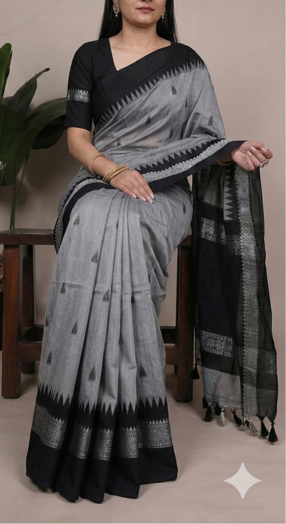 Woman wearing a gray and black saree with a plant in the background