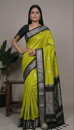 Load image into Gallery viewer, Woman wearing a green and black saree with a plant in the background