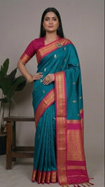 Load image into Gallery viewer, Woman wearing a blue and pink saree with a plant in the background