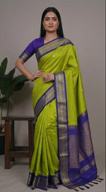 Load image into Gallery viewer, Woman wearing a green and purple saree with a plant in the background
