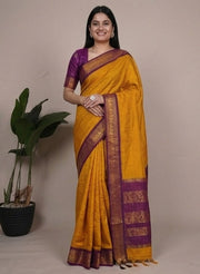 Woman wearing a yellow and purple saree with plants in the background
