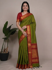 Woman wearing a green and red saree with a plain background
