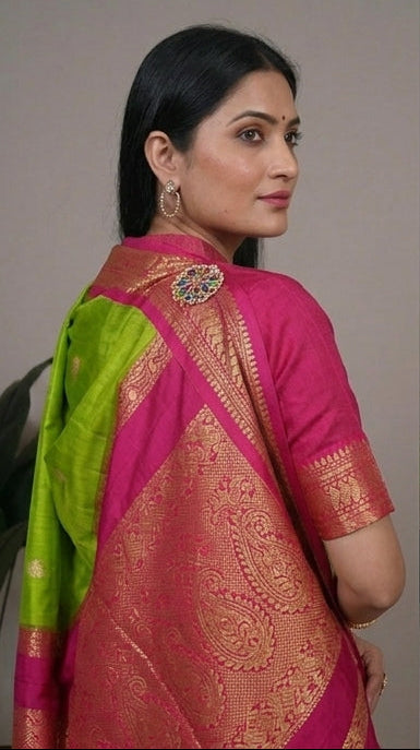 Woman wearing a green and pink saree with a plant in the background