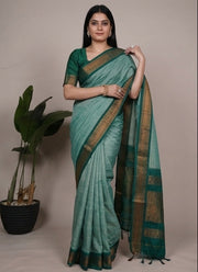Woman wearing a green saree with a plant in the background