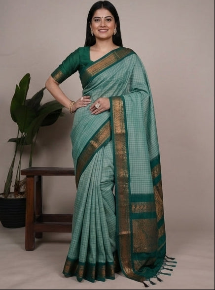 Woman wearing a green saree with a plant in the background