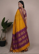 Load image into Gallery viewer, Woman wearing a yellow and purple saree with plants in the background