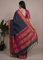 Load image into Gallery viewer, Woman wearing a blue saree with pink and red border, sitting and posing against a neutral background.