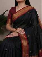 Load image into Gallery viewer, Woman wearing a black saree with a maroon blouse, posing against a neutral background.