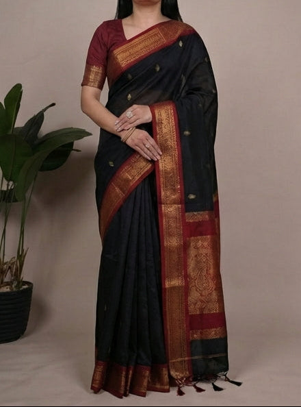 Woman wearing a black saree with a maroon blouse, posing against a neutral background.