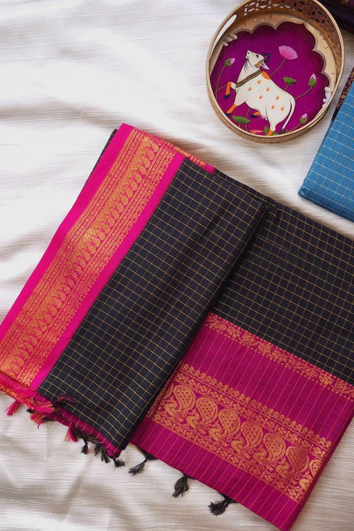 Black and pink checkered Gadwal Silk Cotton saree with a decorative plate in the background